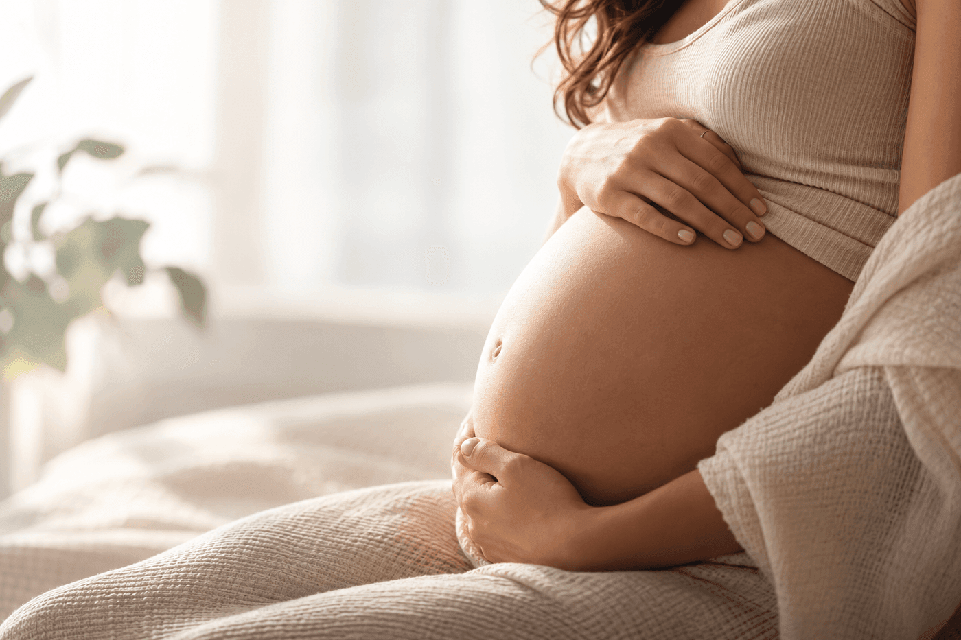 Gestante em momento de cuidado, com as mãos sobre a barriga